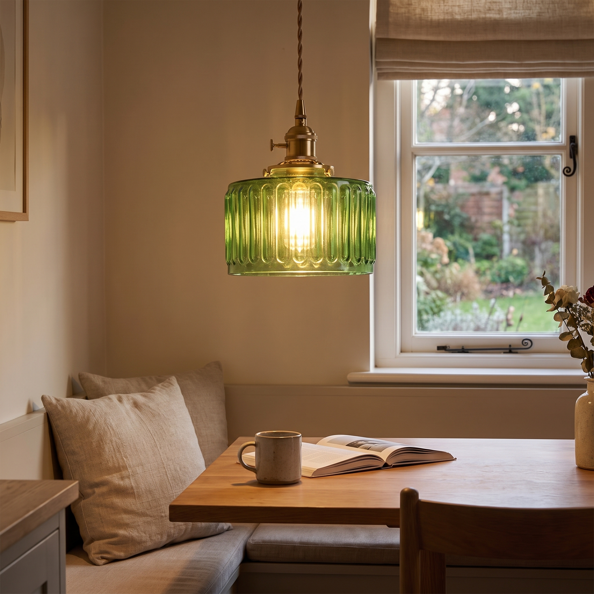 Green glass pendant glowing over a breakfast nook